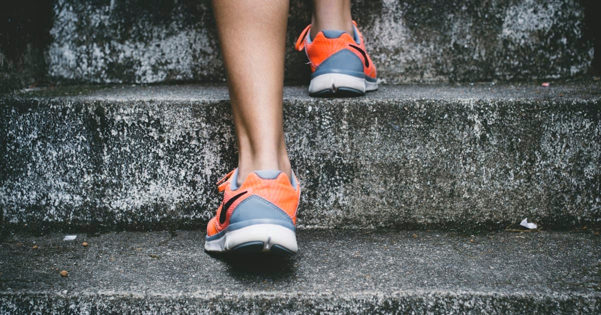 Close-up of bright orange Nike running shoes climbing gray concrete stairs during outdoor training