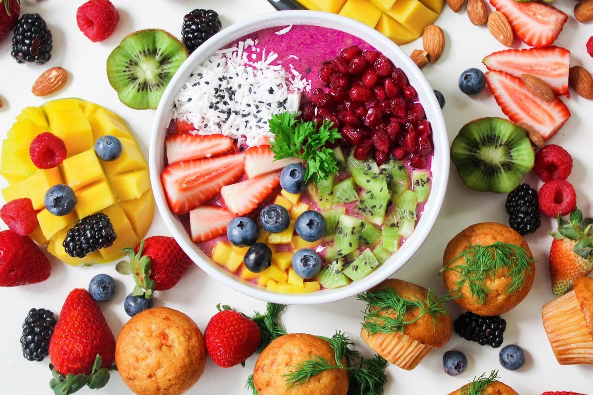 Colorful smoothie bowl topped with fresh fruit slices in a white bowl on a table